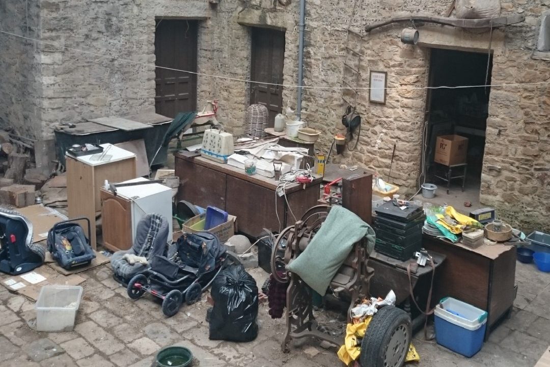 Furniture, appliances and household items gathered in the cobbled courtyard of an old stone property