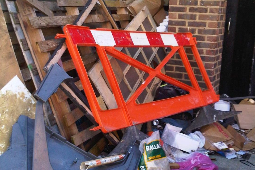 Timber, pallets and a road barrier stacked against a wall, cleared from a site